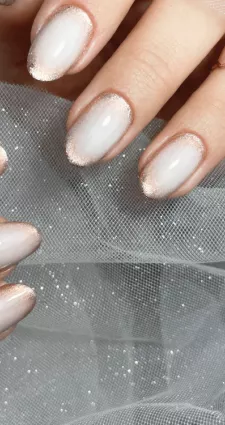 Photo d'ongles manucurée avec un vernis rose pale et champagne.